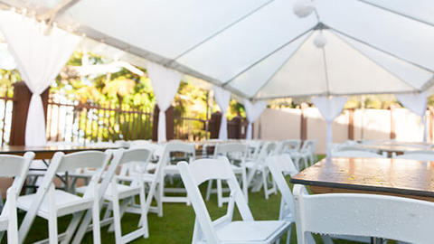 white tables and chairs under an event tent