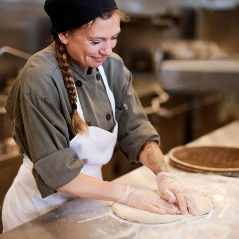 cook working with pizza dough in kitchen