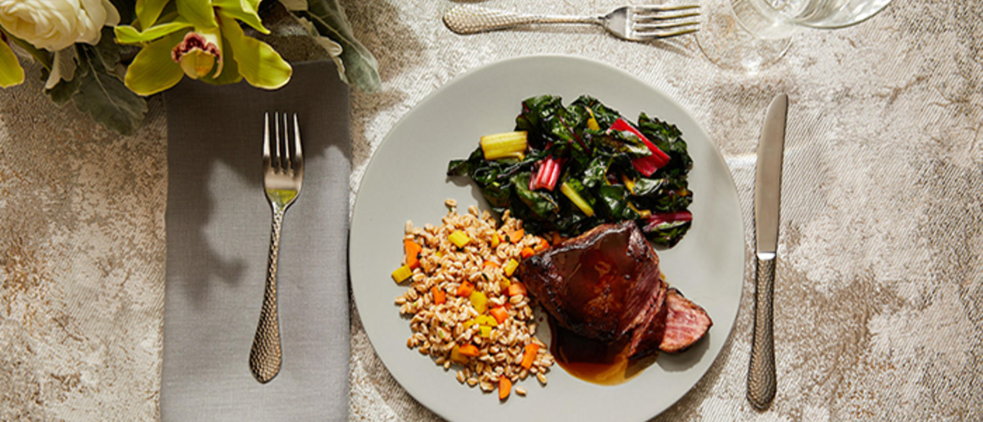 table setting with a white plate that has tenderloin, rice, and assorted veggies